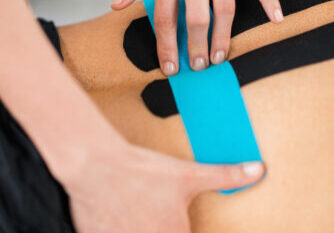 Physical therapist placing kinesio tape on patient's back